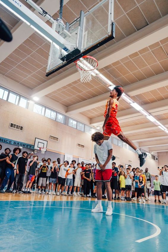 Dunk au-dessus d'un joueur devant le public du All Riviera Game